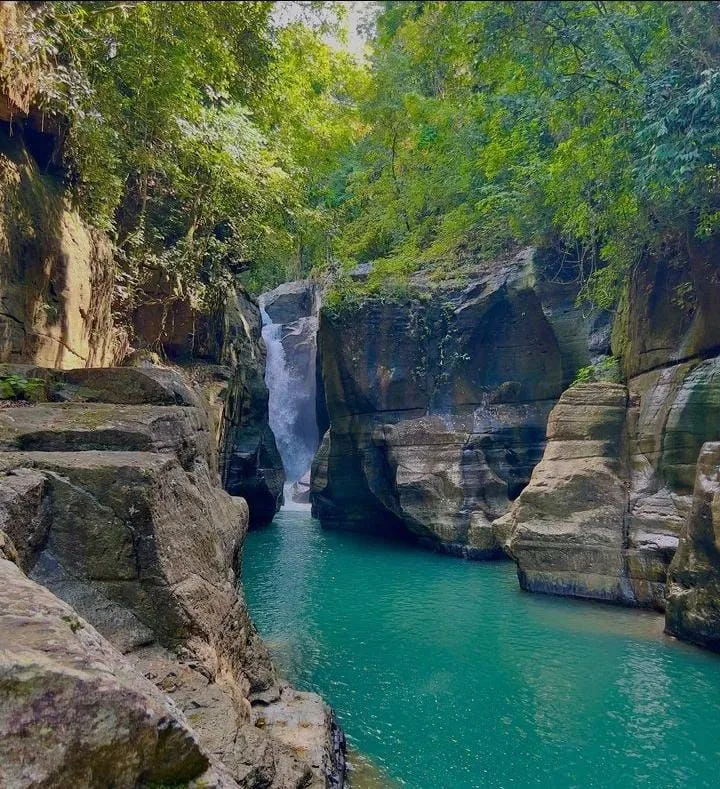 A waterfall pouring into the emerald pool of Cunca Wulang canyon