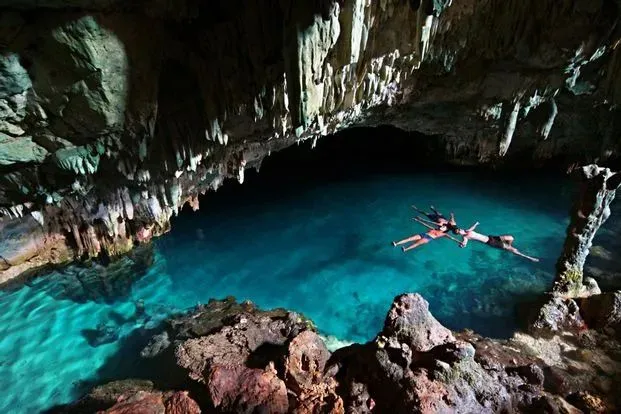 A swimmer floating in the blue pool inside Rangko Cave