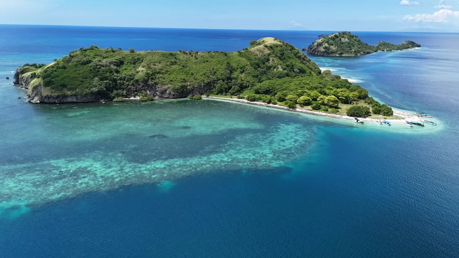 Aerial view of a forested island and coral reef in Riung's 17 Islands