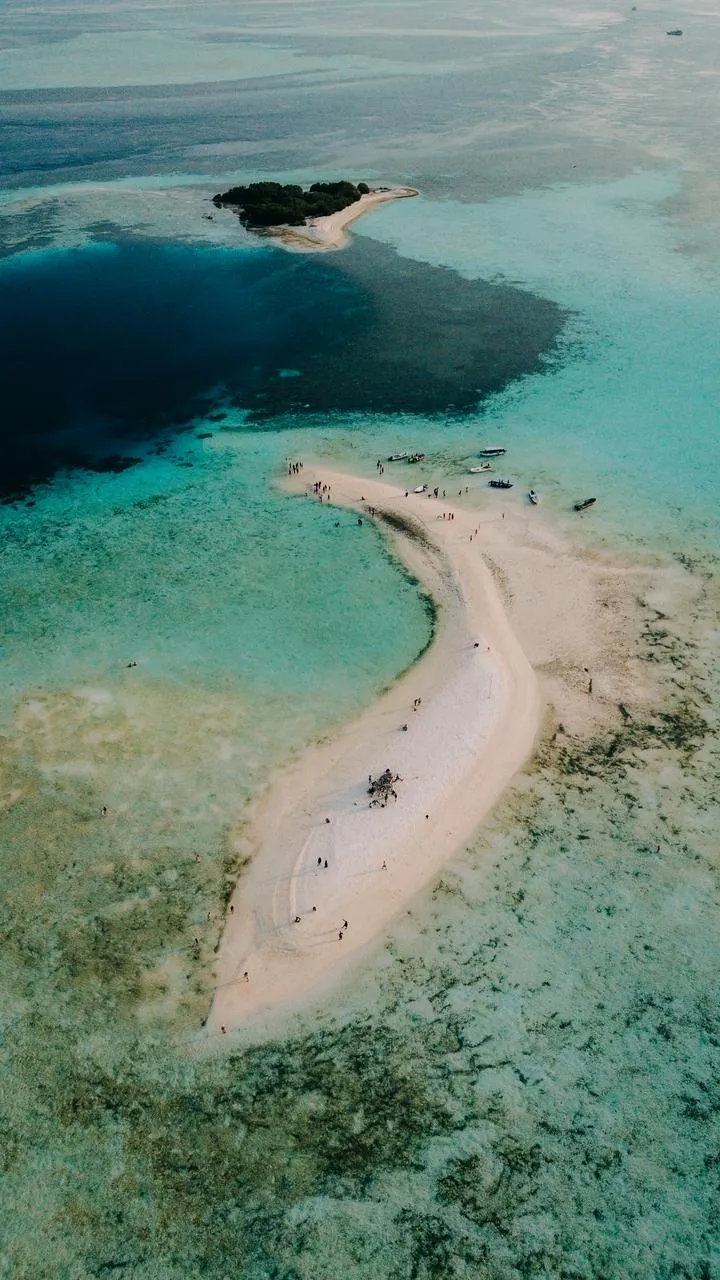 The curved white sandbar of Taka Makassar in a turquoise lagoon
