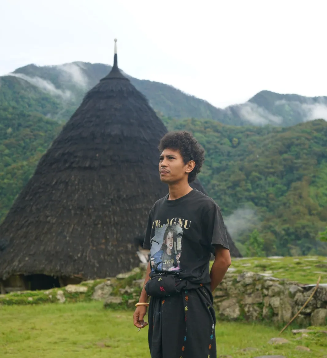 A guide before the cone-roofed houses of Wae Rebo
